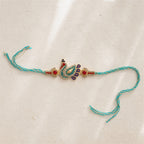 Decorative peacock feather rakhi on a beige background