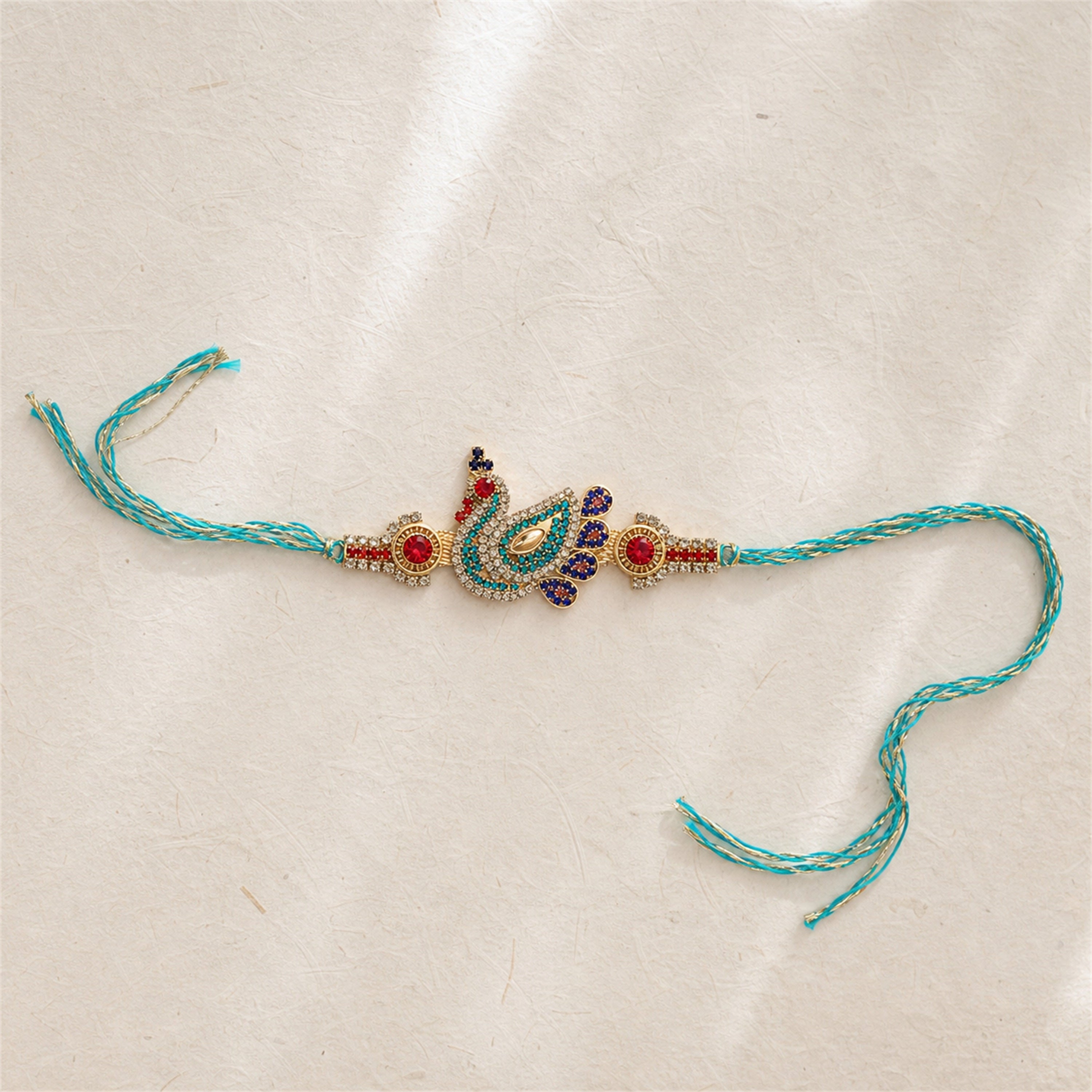 Decorative peacock feather rakhi on a beige background